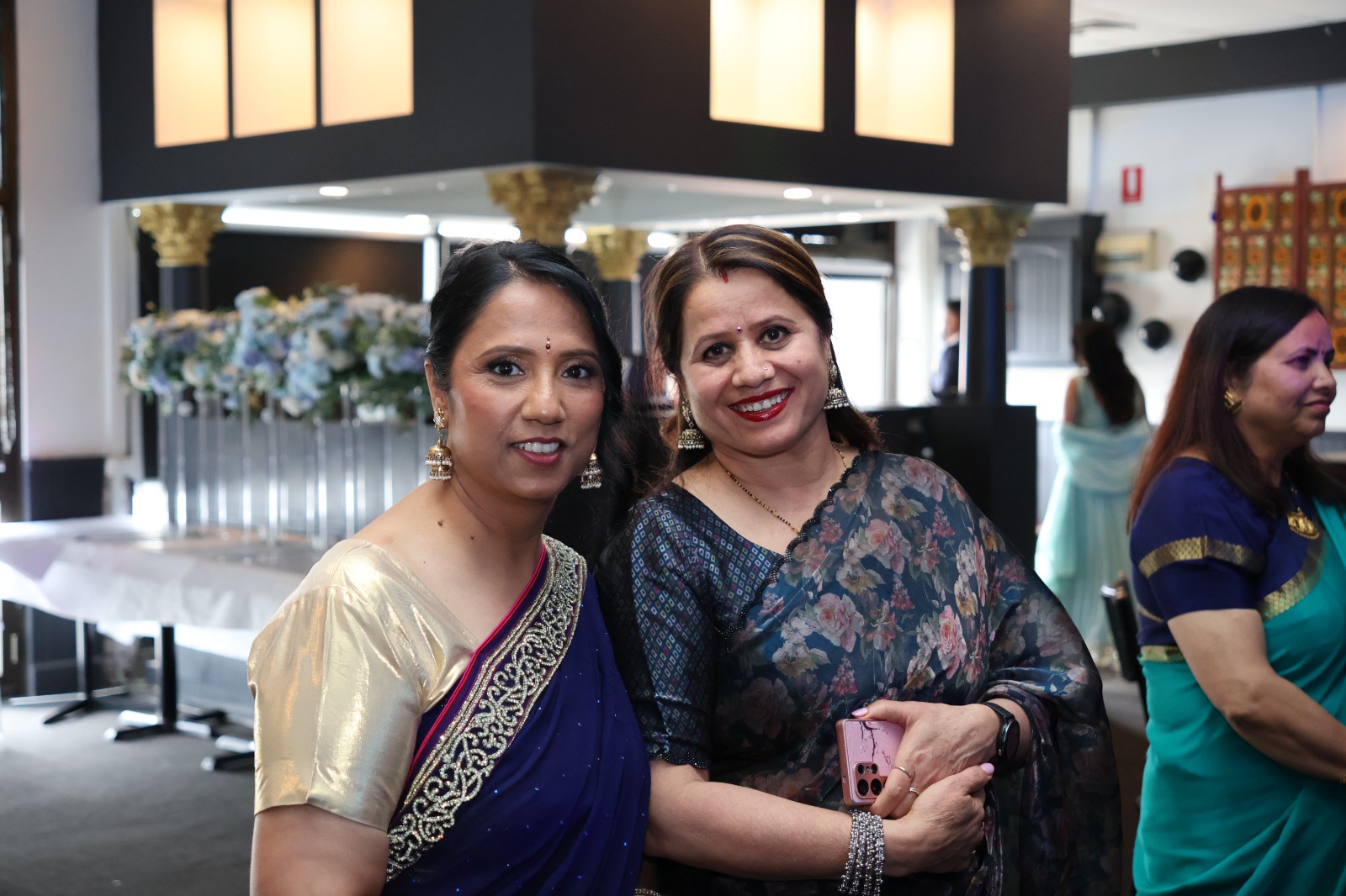 Two guests in sarees smiling together