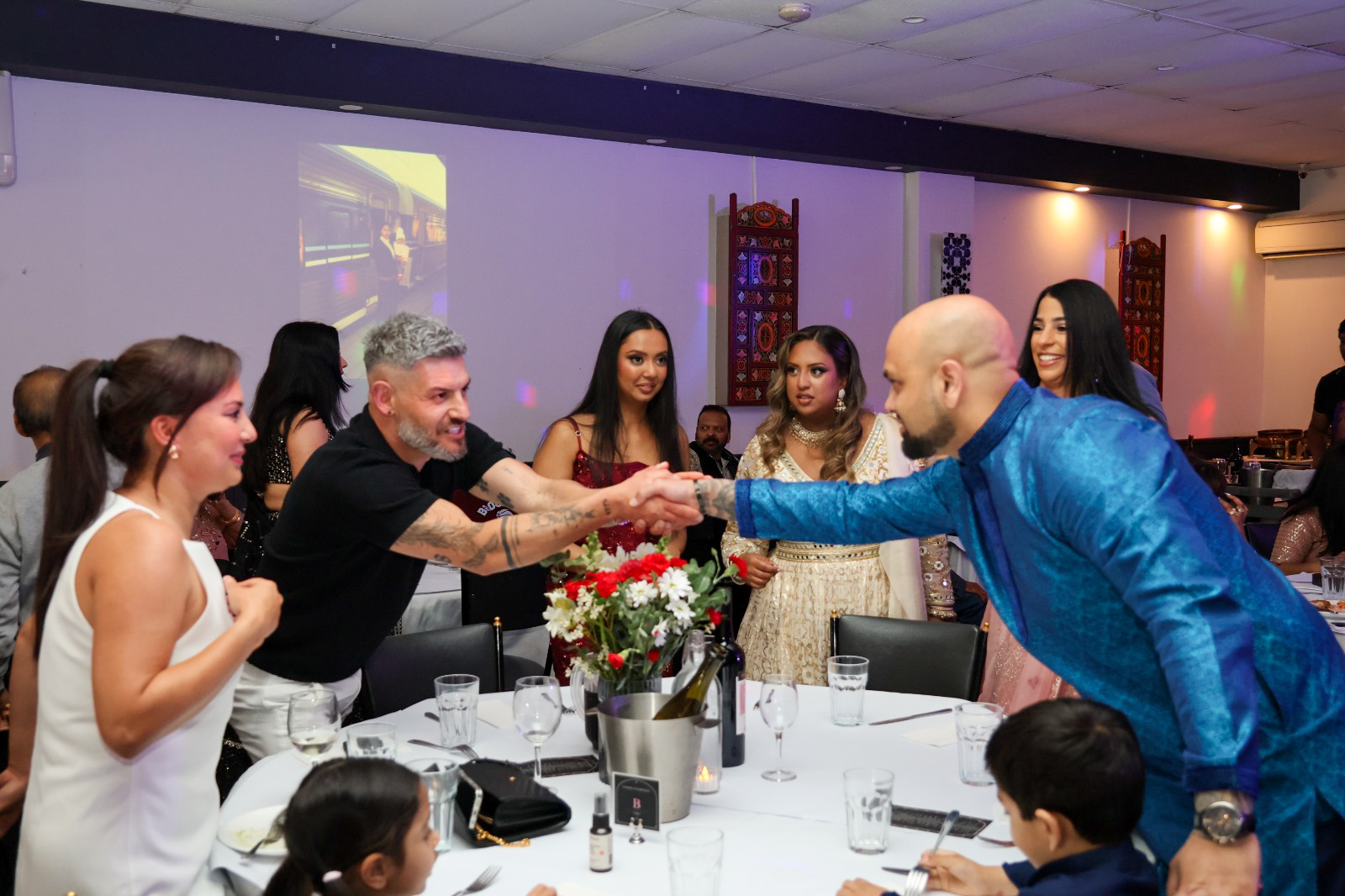 Guests shaking hands across a dinner table