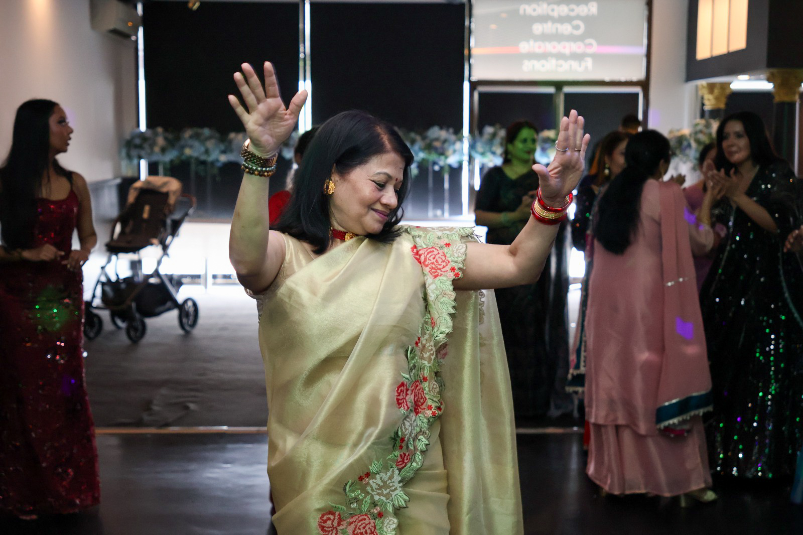 Guest in a gold saree dancing with hands raised