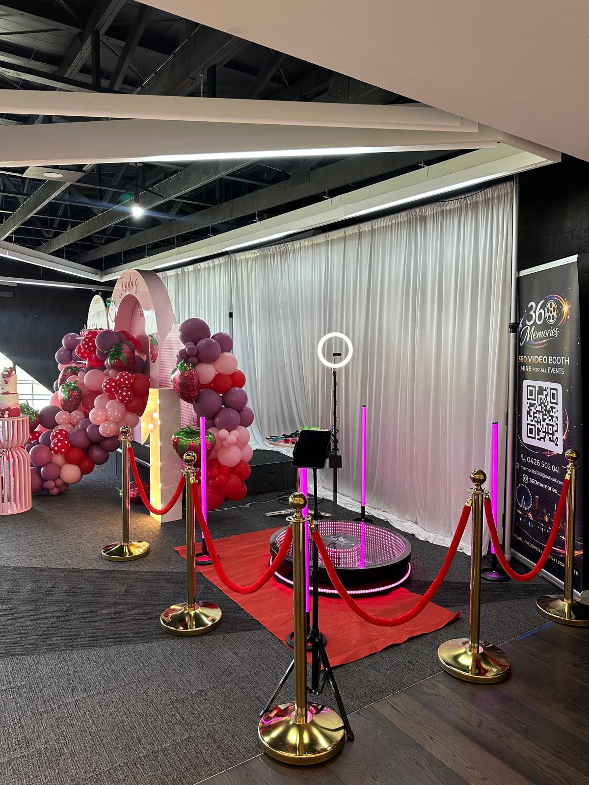 360 video booth setup at birthday celebration with balloon arch and red carpet