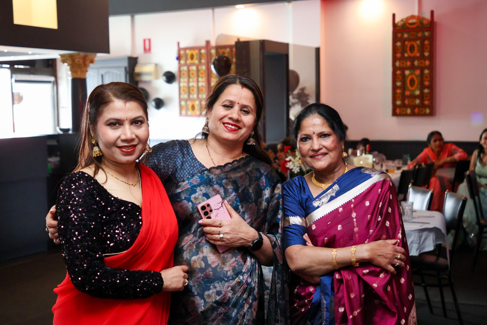 Three guests in sarees posing together at the celebration