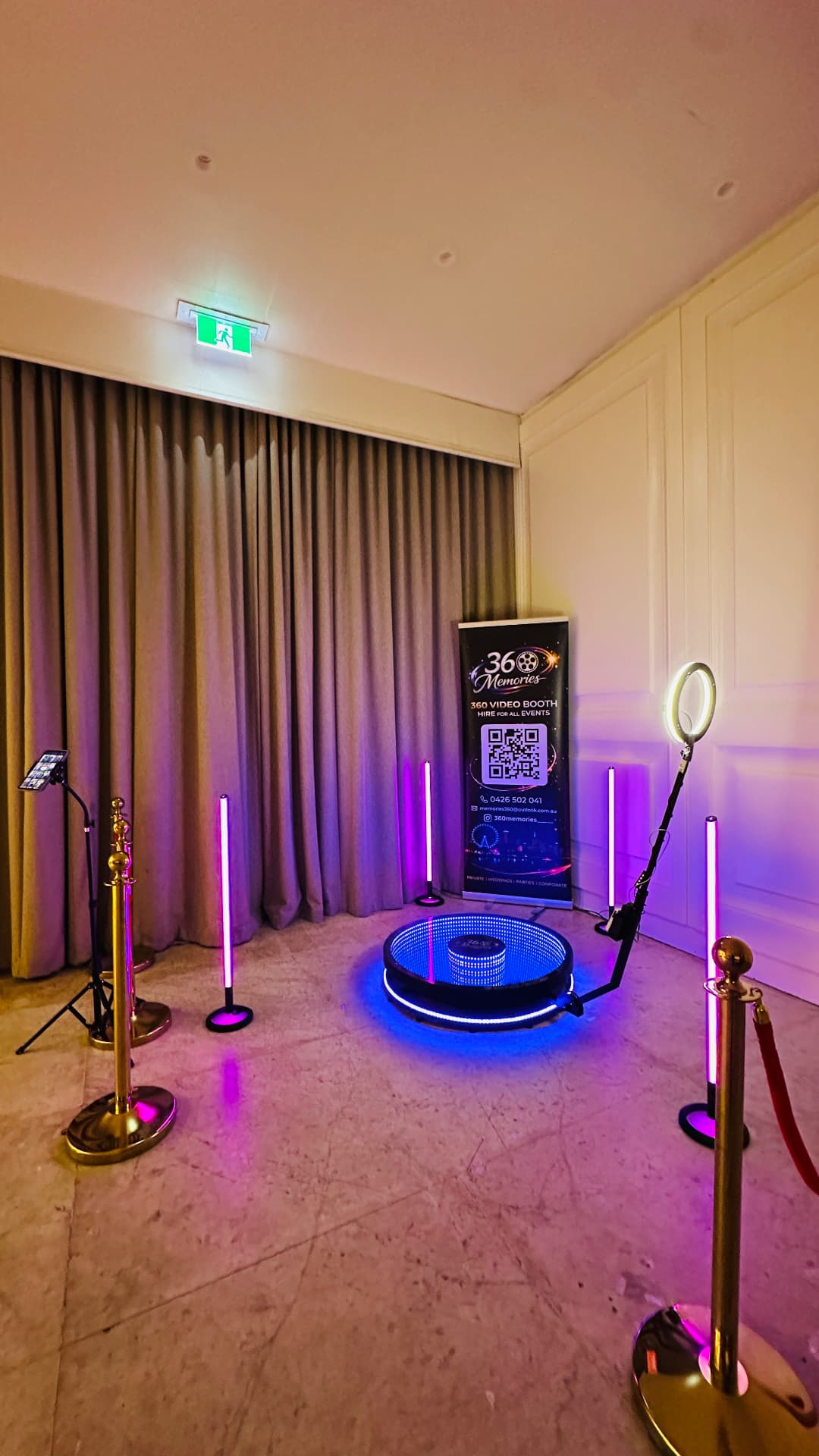 360 video booth with purple lighting and gold stanchions in a curtained event room