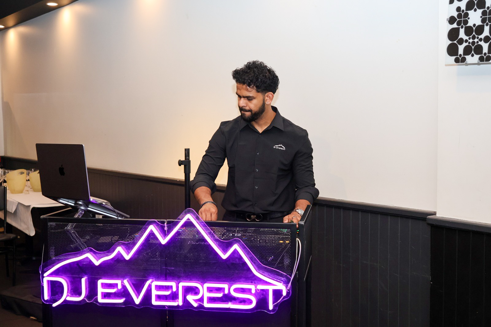 DJ at his neon-lit booth setting up the music