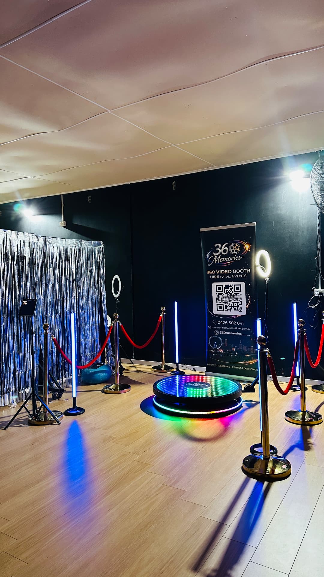 Illuminated 360 video booth with a silver backdrop and red velvet ropes