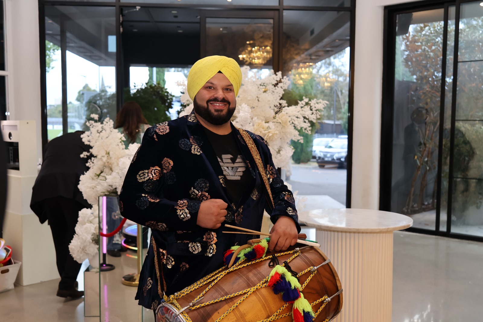 Dhol player in a yellow turban greeting guests