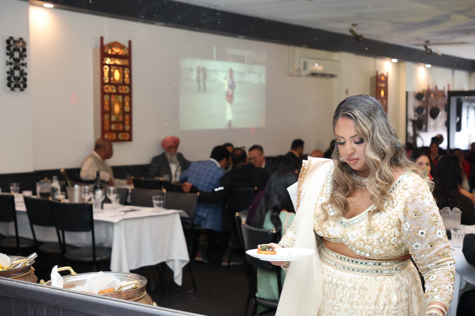 Guest in an embroidered outfit serving food at the buffet
